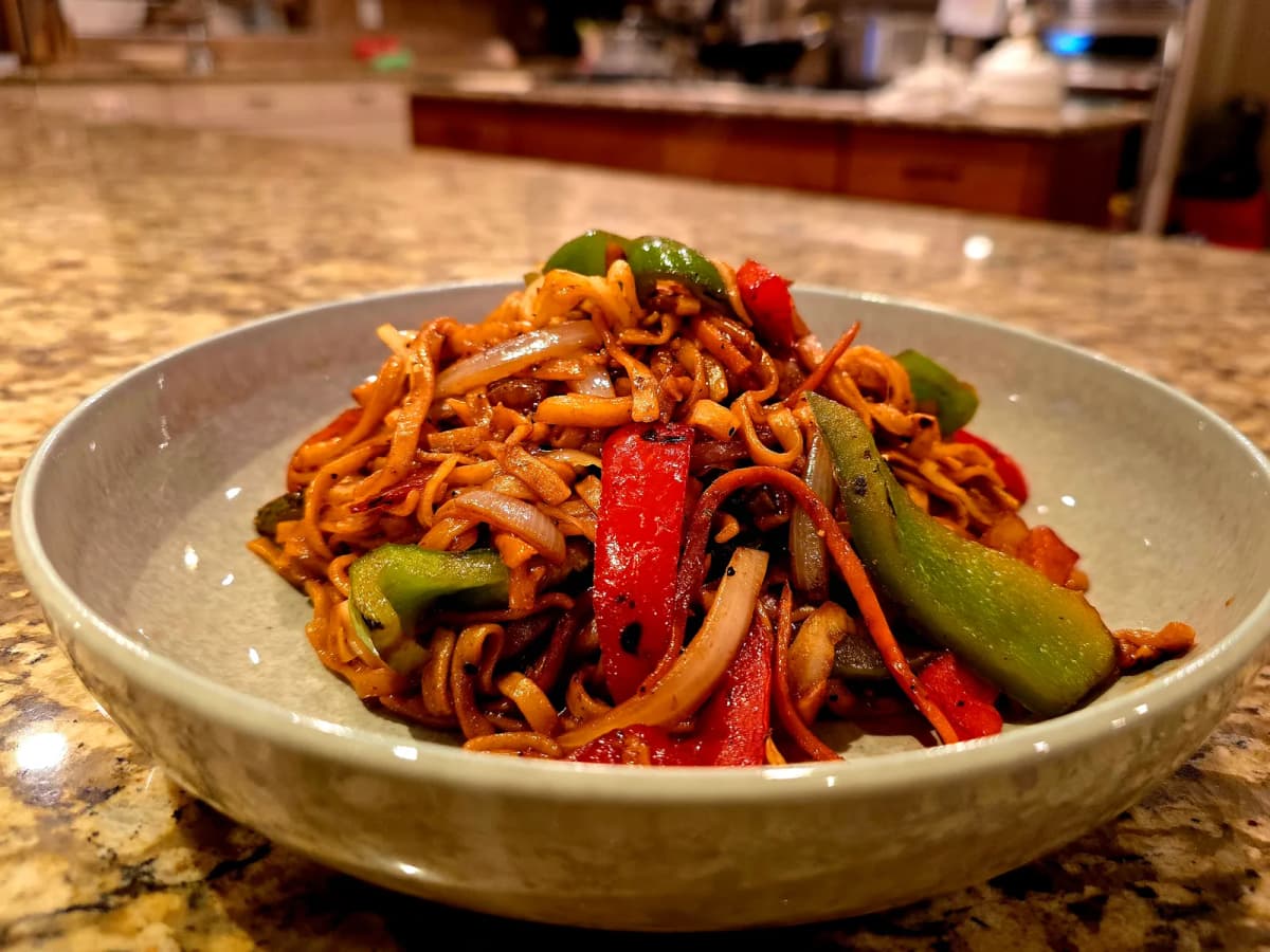 Steaming bowl of authentic vegetable chow mein with crispy noodles, fresh vegetables, and savory sauce