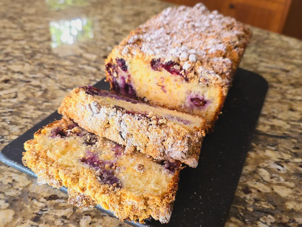 Moist blueberry loaf with a golden-brown crust studded with fresh blueberries, sliced to reveal tender crumb