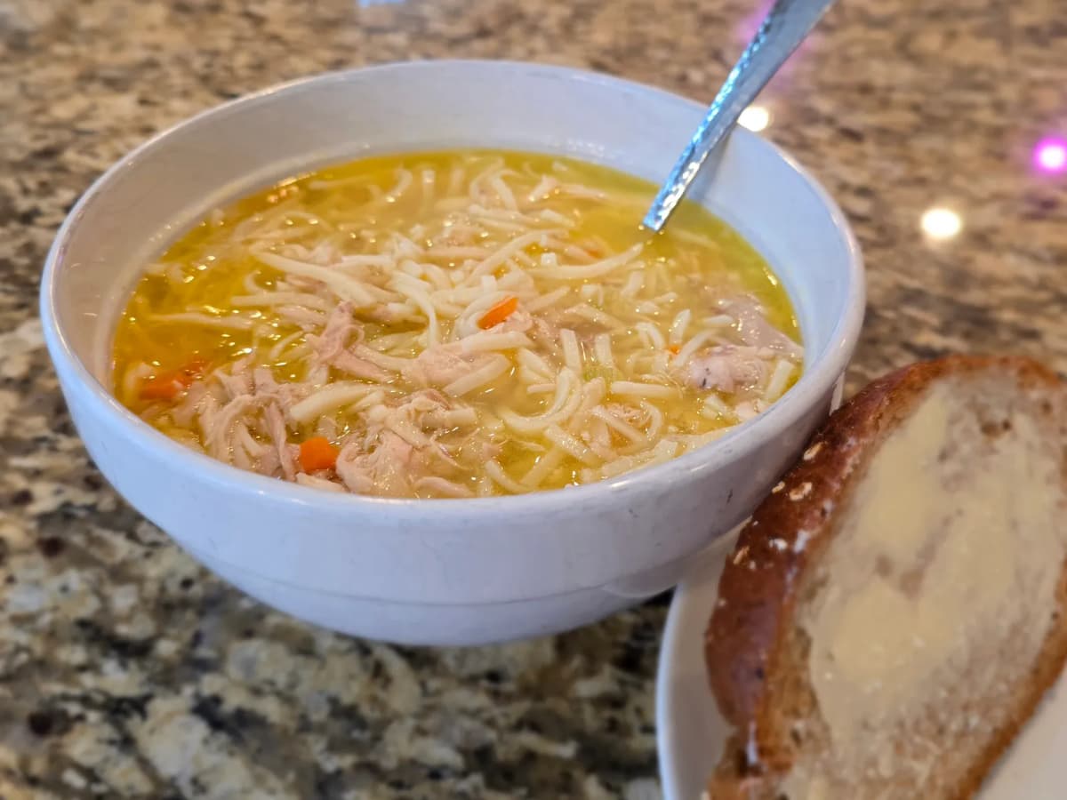 Steaming bowl of traditional prairie chicken noodle soup with homemade egg noodles and vegetables