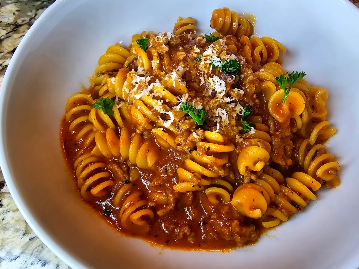 Creamy one pot beef pasta with ground beef, tomato sauce, and fresh herbs in a large pot