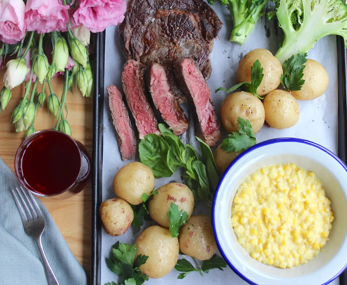 Perfect golden-brown seared ribeye steak on a white plate with herb butter and fresh rosemary garnish
