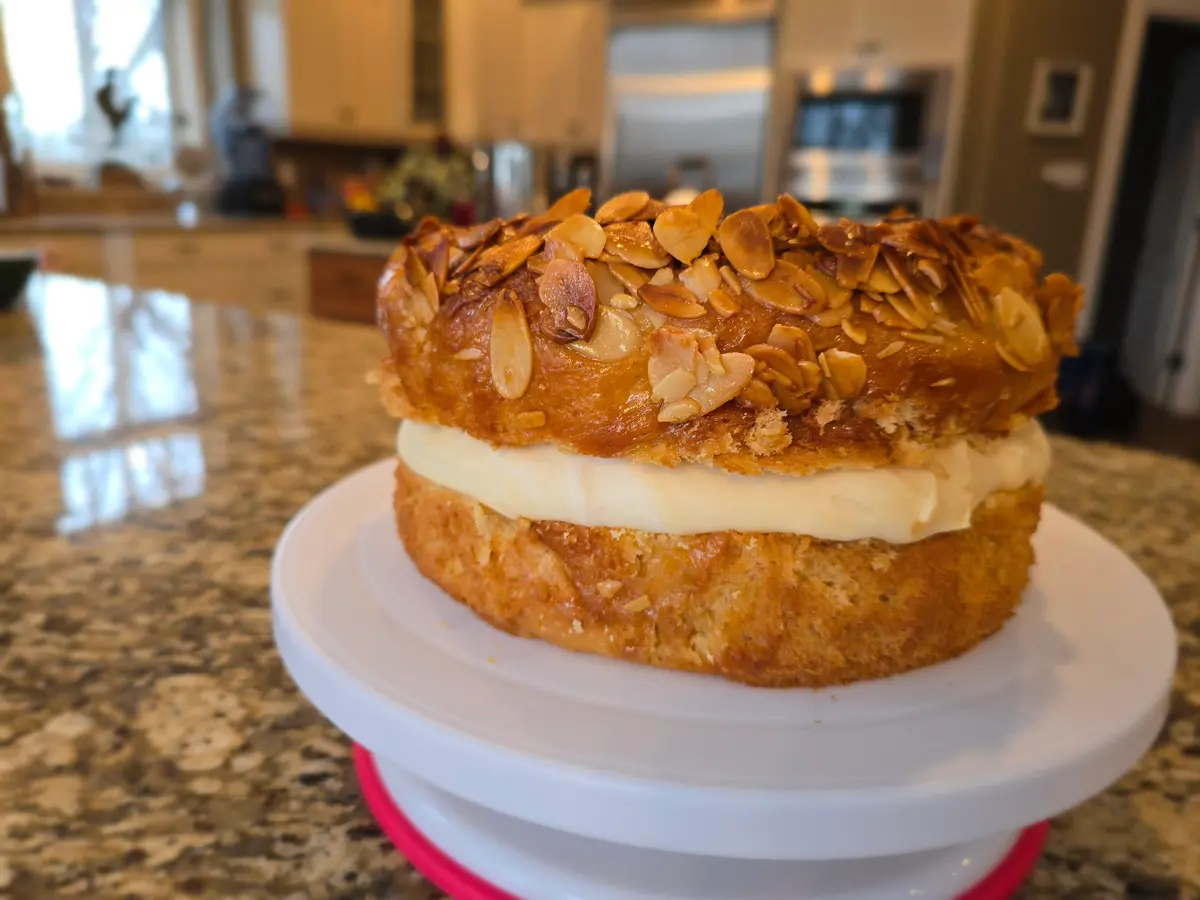 Golden Bee Sting Cake with crispy almond topping, creamy Bavarian filling, and soft brioche base on a white plate