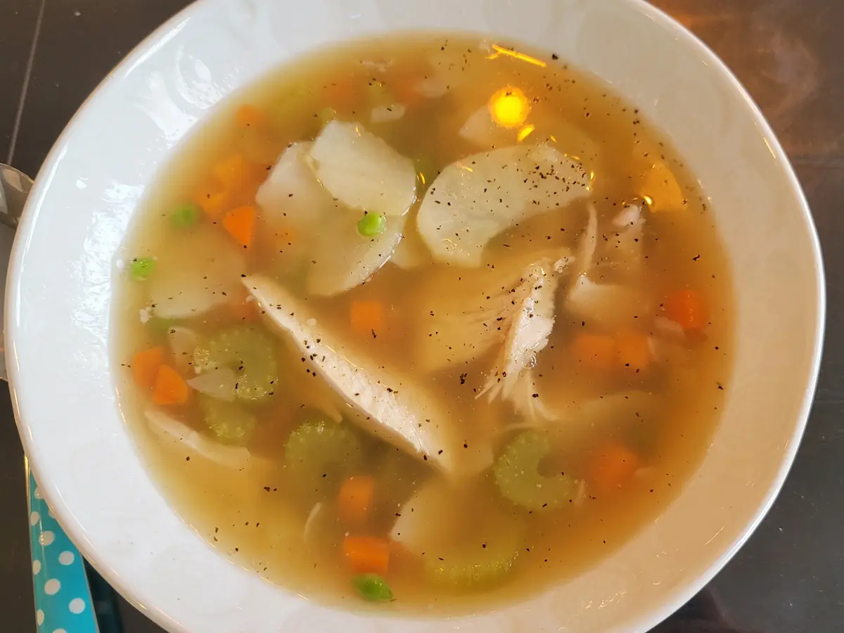 Steaming bowl of turkey soup with shredded turkey, potatoes, and colorful vegetables in a creamy broth