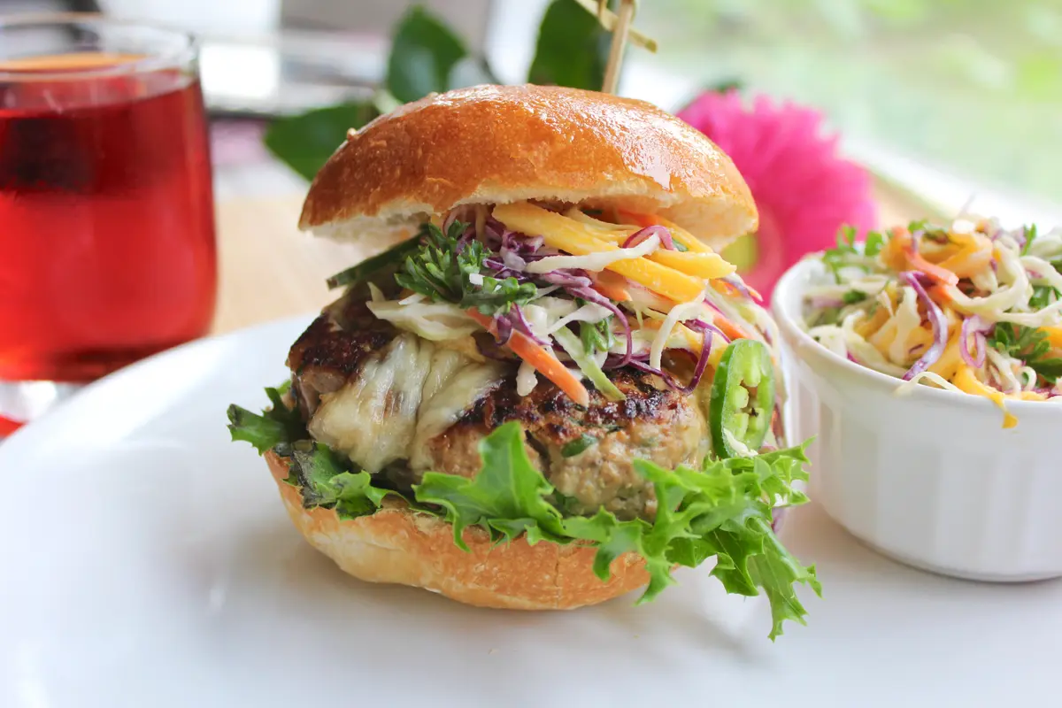 Juicy umami turkey burger on a bun with melted cheese and fresh toppings, served with fries on a white plate