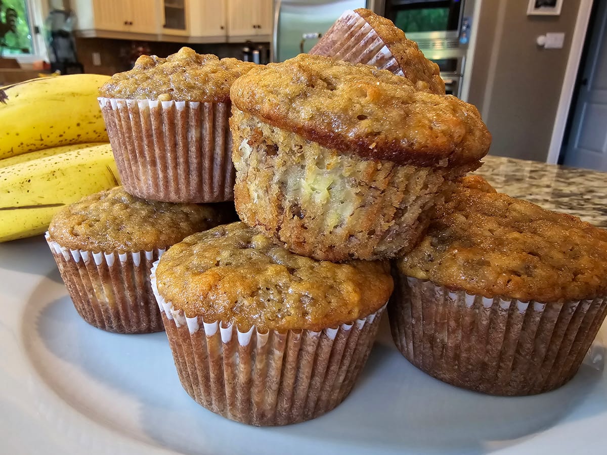 Golden-brown banana nut muffins in a muffin tin, showing moist crumb texture with visible walnuts