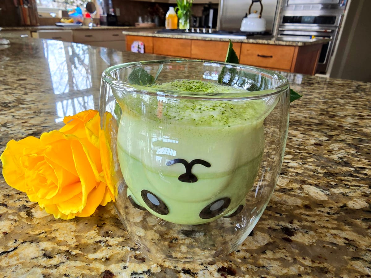 Creamy matcha green tea latte in a white cup with frothy foam top and cinnamon garnish