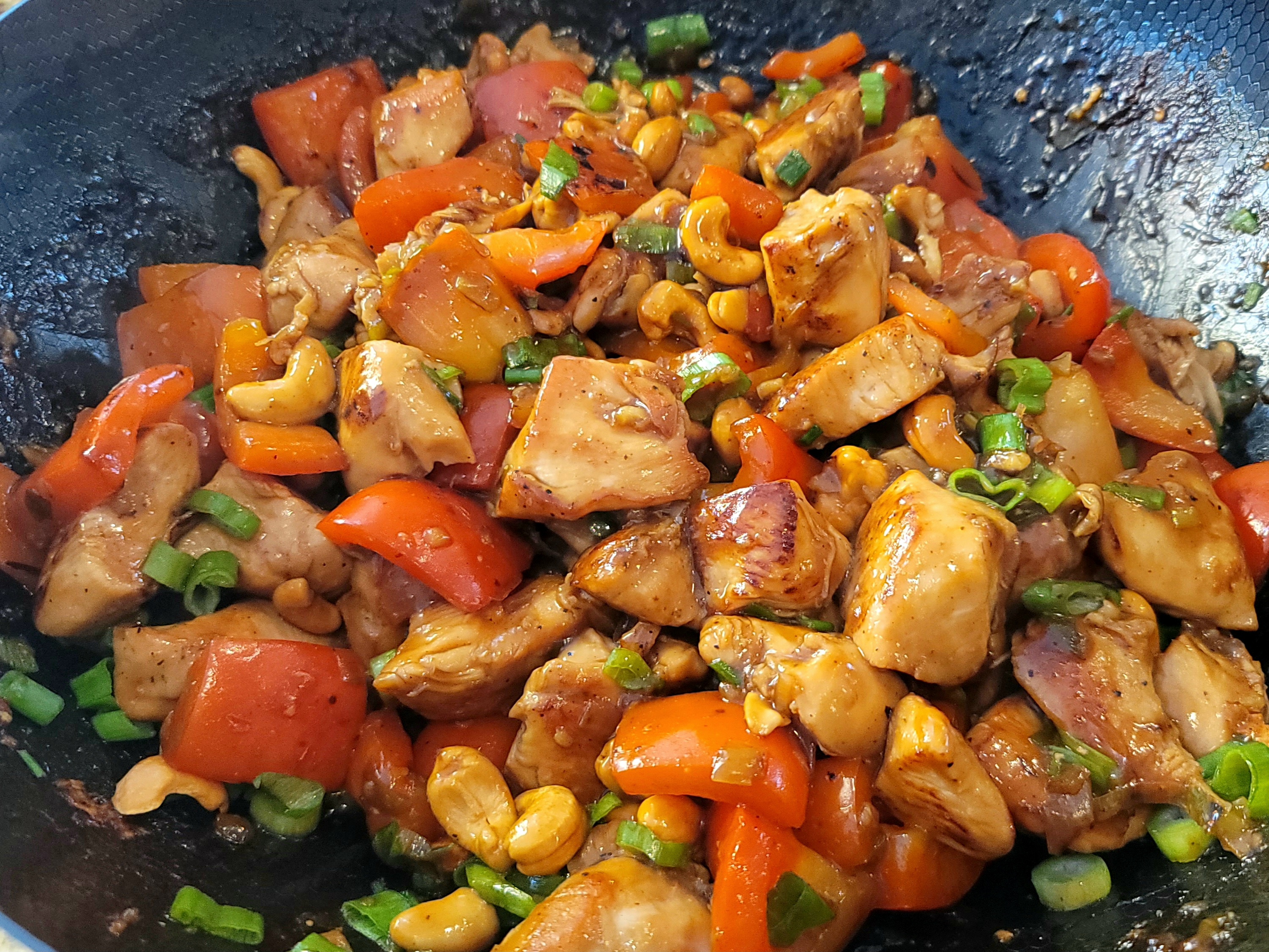Cashew chicken stir-fry with red and green bell peppers, roasted cashews, and green onions in a glossy brown sauce