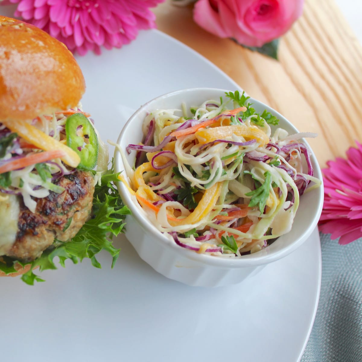 Creamy coleslaw with shredded cabbage and tangy dressing in a white bowl, topped with fresh herbs
