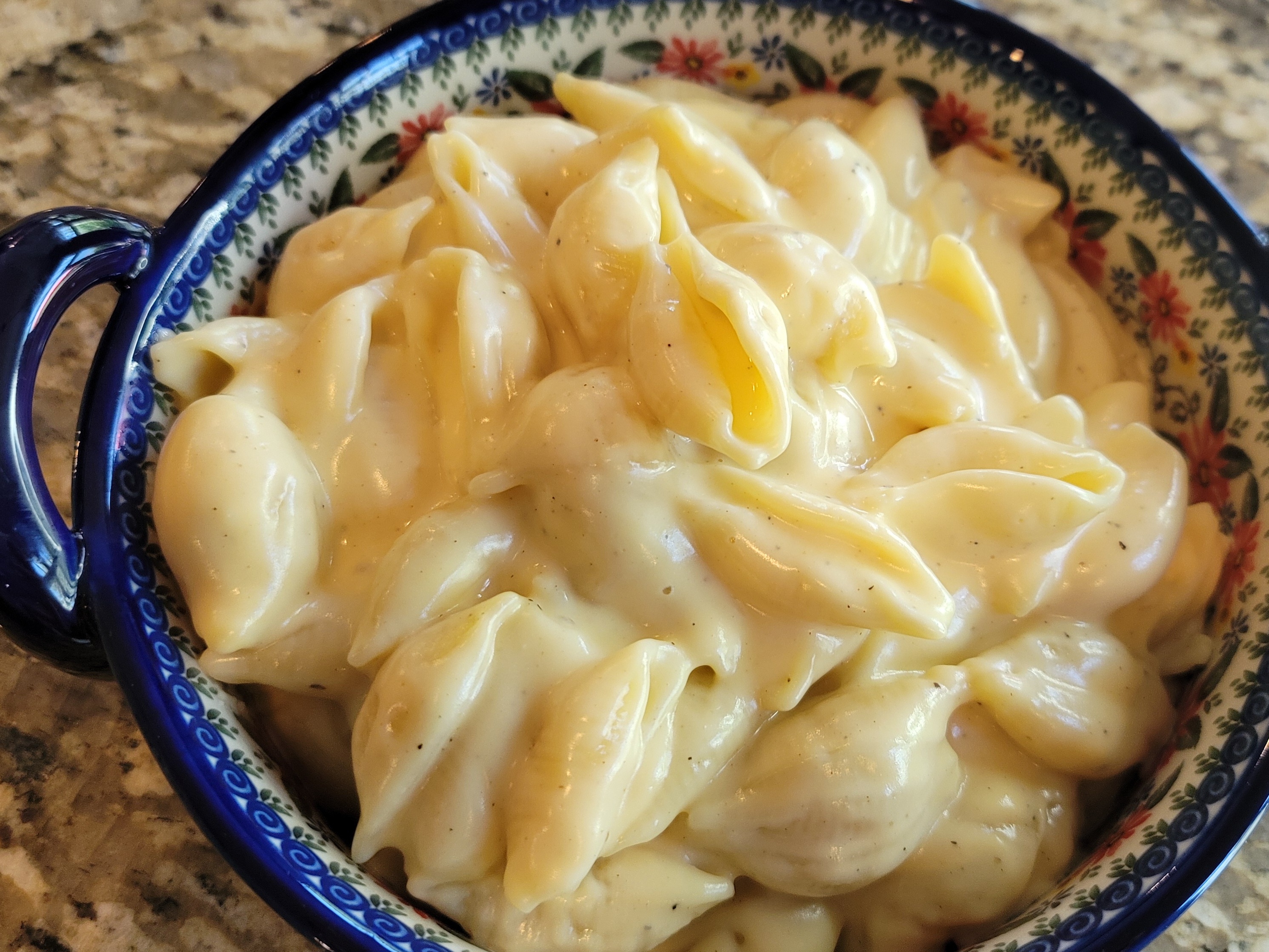 Creamy copycat Panera mac and cheese in a white bowl, showing smooth cheese sauce coating pasta shells