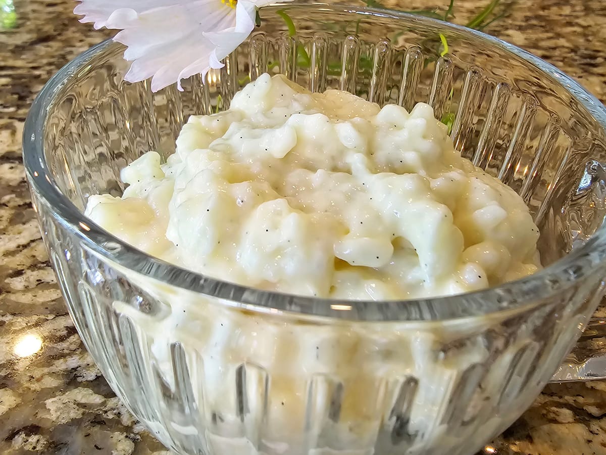 Creamy vanilla rice pudding in a white bowl with a spoon, showing soft rice grains in silky custard base