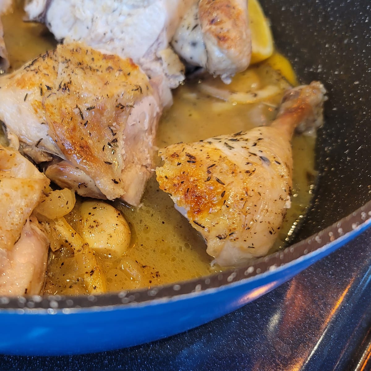 Golden roasted lemon chicken with crispy skin on a white plate, garnished with fresh lemon slices and herbs