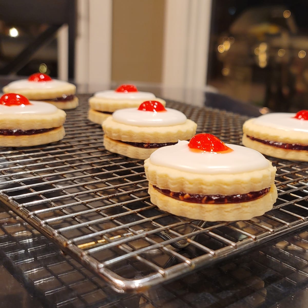 Golden buttery Empire cookies stacked and arranged, showing raspberry jam filling between delicate shortbread layers with almond extract flavor