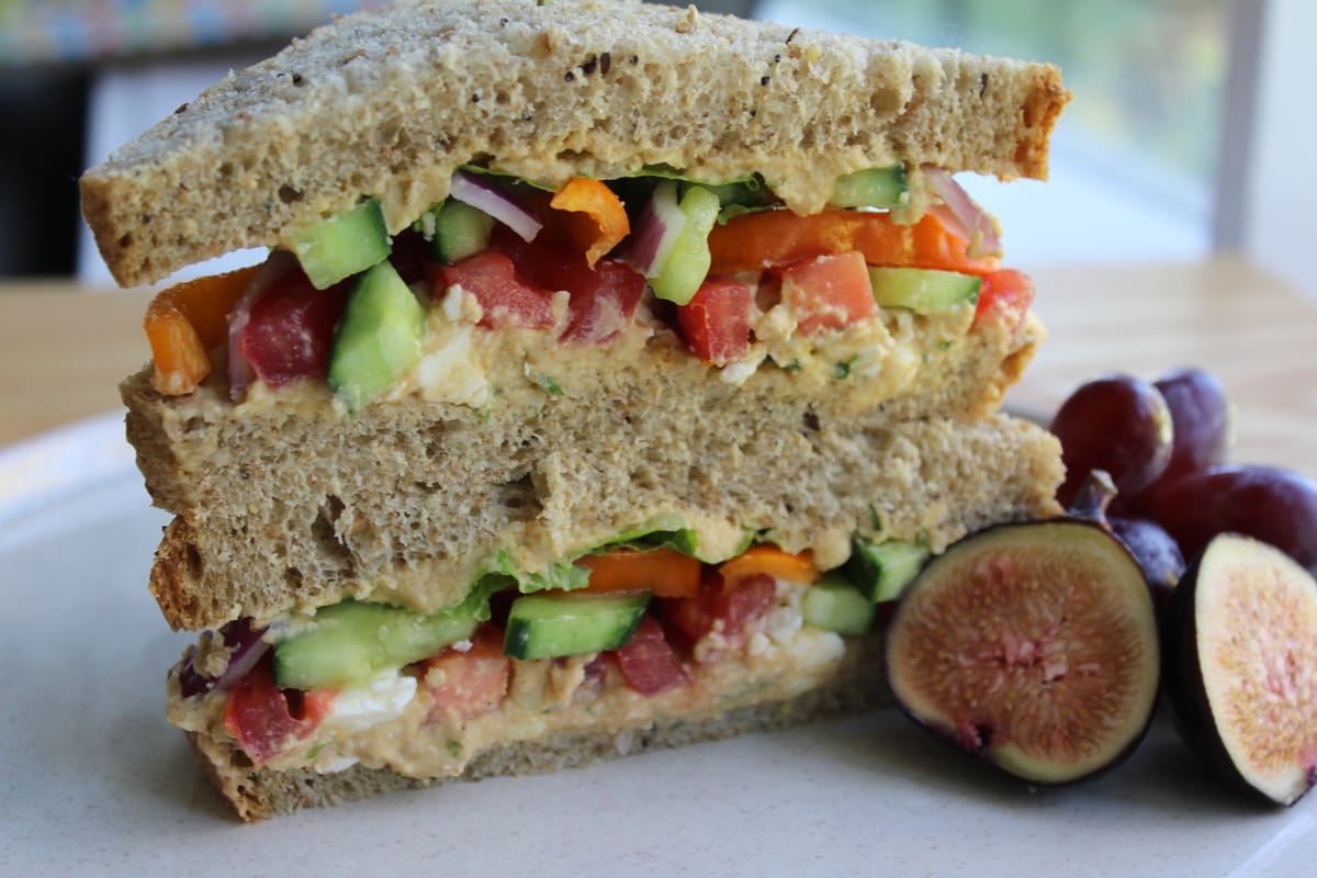 Hearty hummus sandwich with creamy hummus, fresh vegetables, and greens on whole grain bread