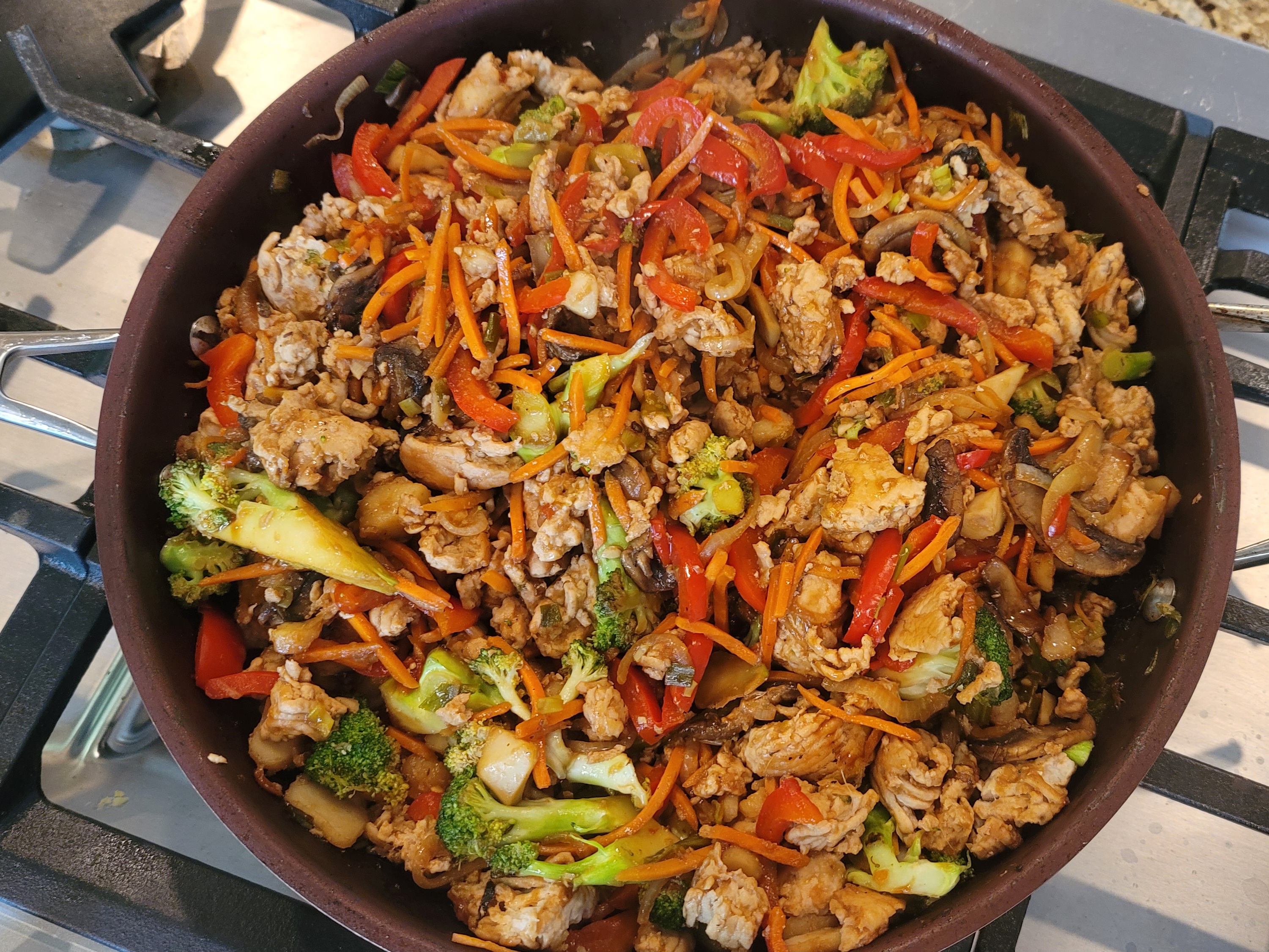 Colorful ground chicken stir-fry with broccoli, bell peppers, carrots, and mushrooms in a wok, garnished with green onions