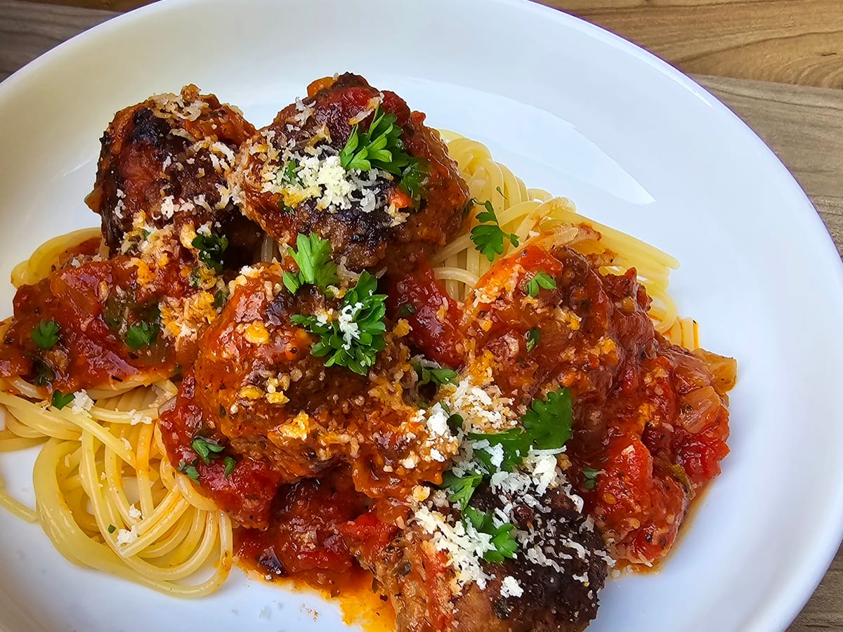 Homemade marinara sauce in a white bowl with fresh basil leaf garnish and rich red tomato color