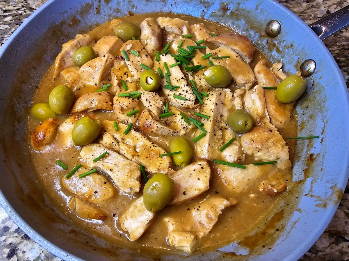Pan-seared lemon chicken piccata with bright lemon-caper sauce, garnished with fresh parsley and lemon slices on a white plate