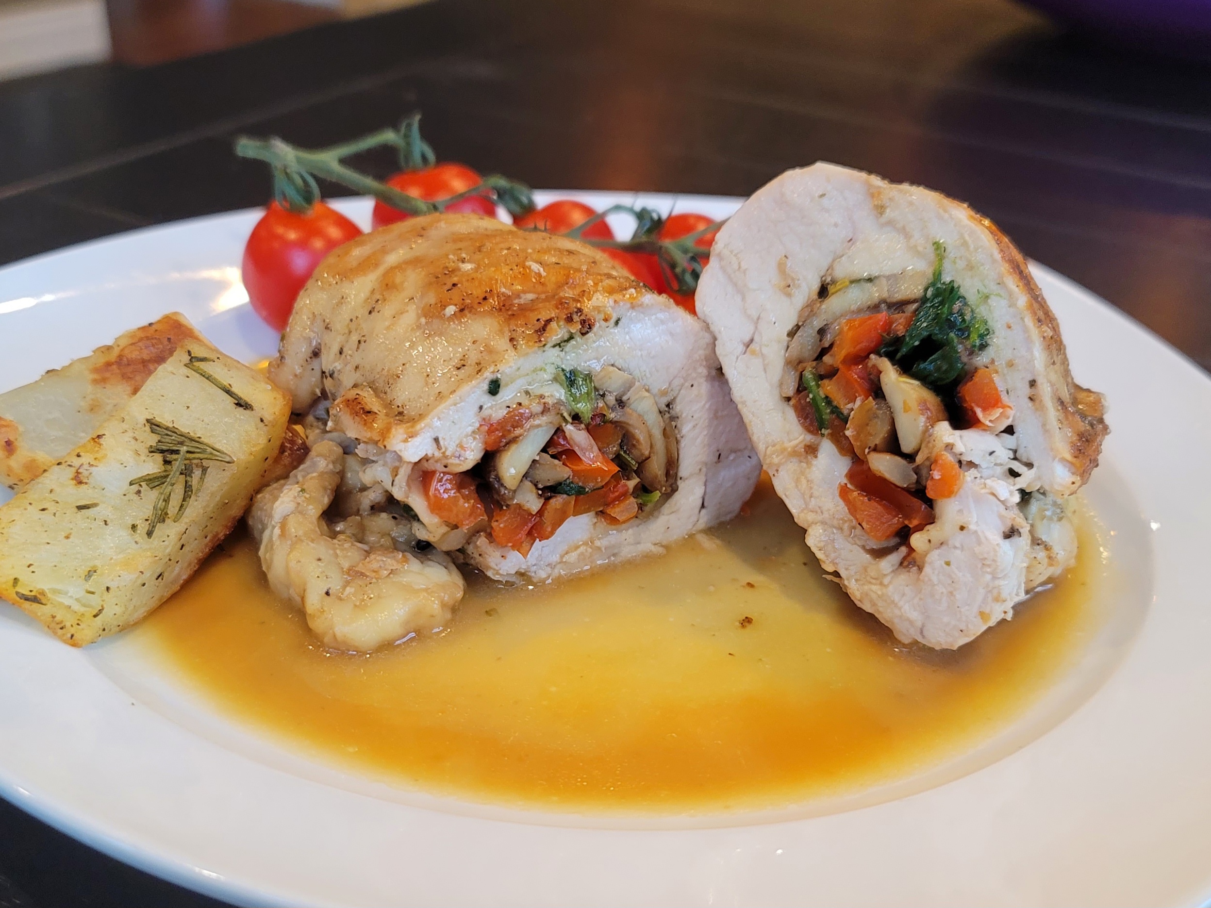 Juicy mushroom stuffed chicken breast with spinach and melted cheese on a white plate with roasted vegetables