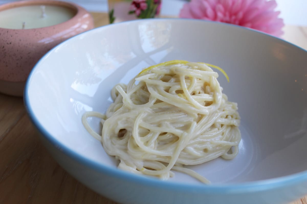 Silky pasta al limone with creamy lemon sauce, fresh basil, and cracked black pepper on a white plate