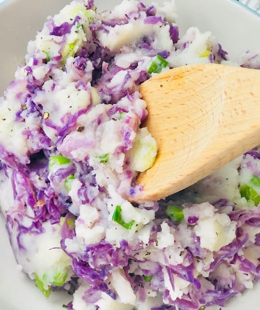 Creamy red cabbage colcannon with purple and white layers of mashed potatoes and red cabbage in a white bowl