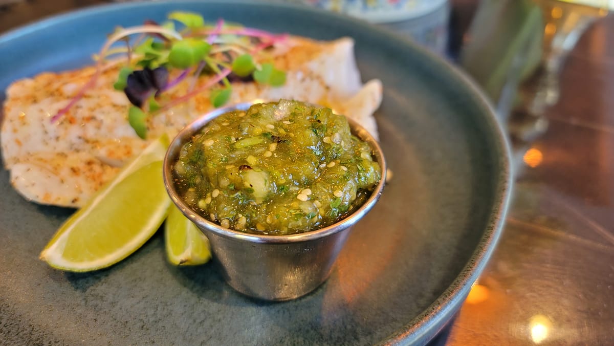Bright green salsa verde with fresh tomatillos in a white bowl, garnished with cilantro