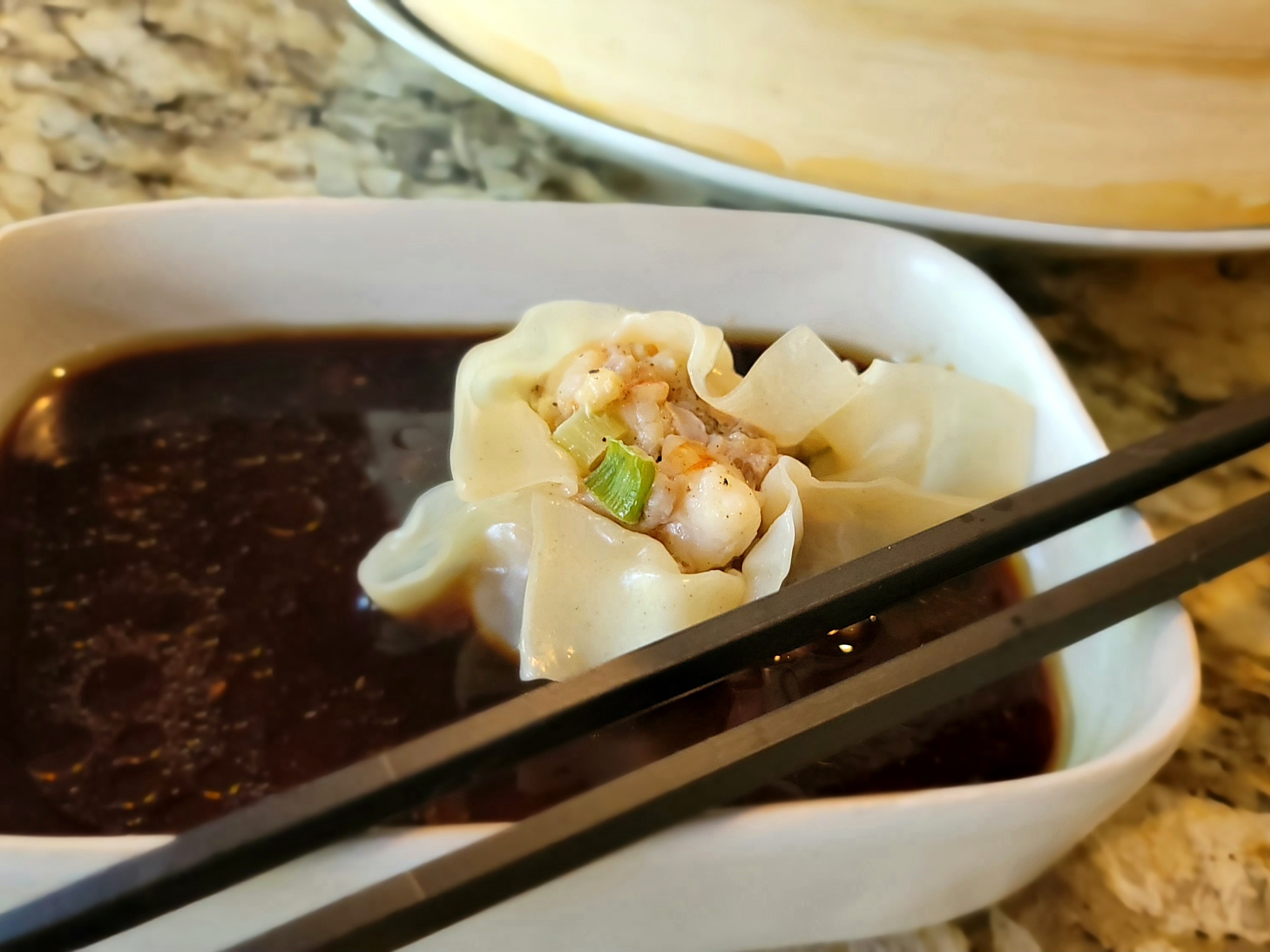 Homemade shrimp and pork dumplings on a white plate with soy dipping sauce and green onions