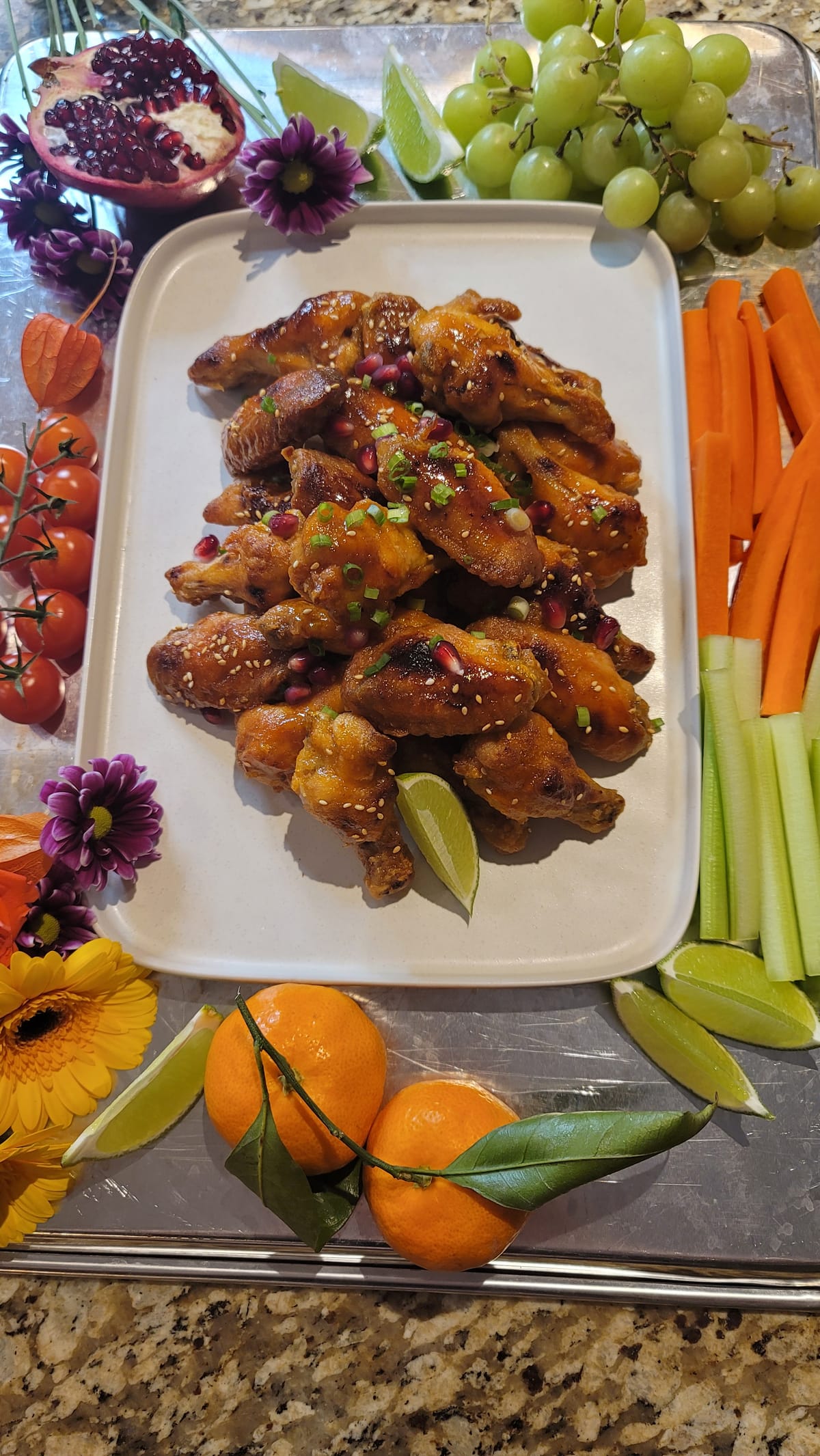 Crispy golden sriracha honey chicken wings piled on a white plate with sesame seeds and fresh green onions