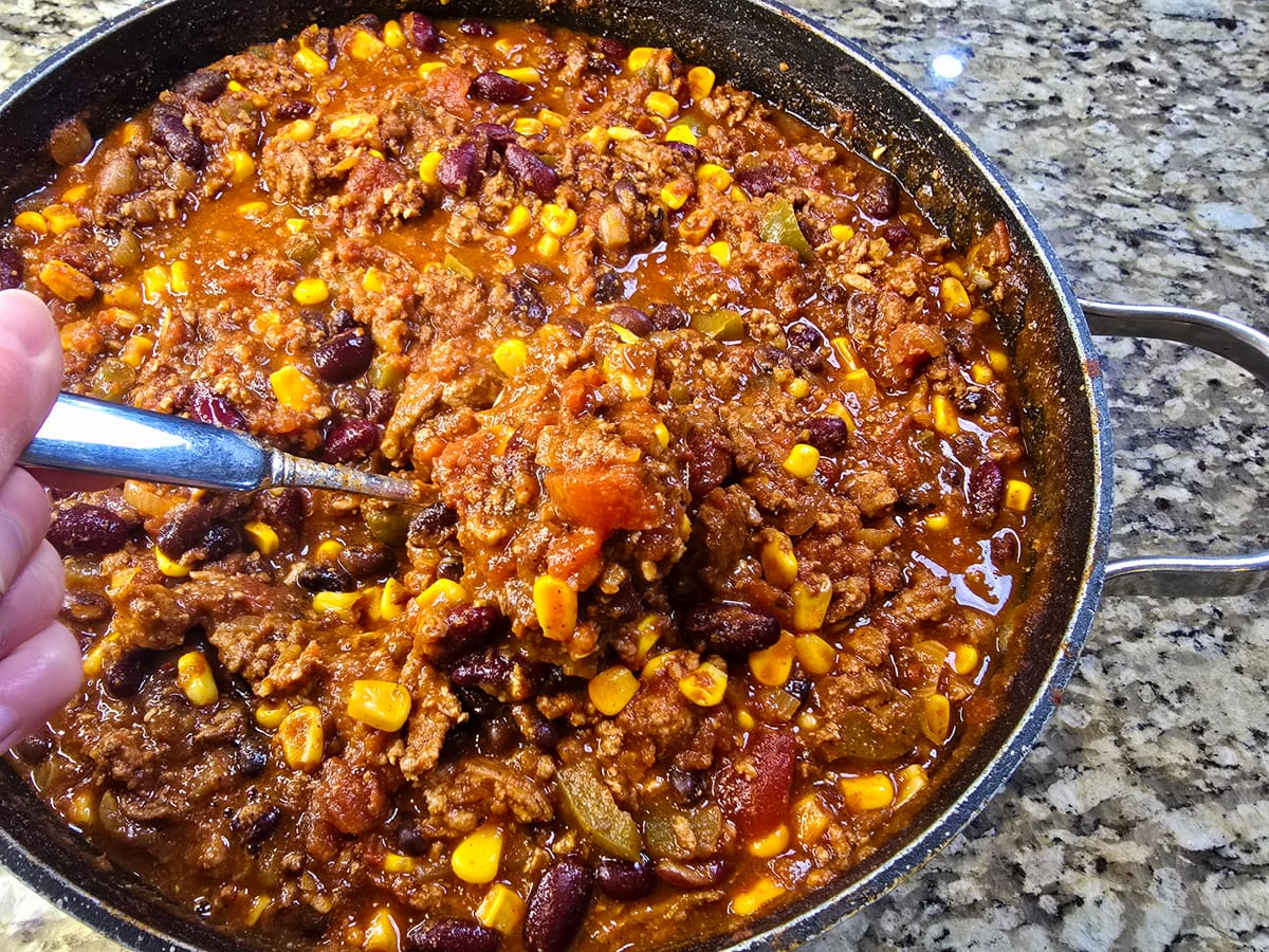 Bowl of best turkey chili with ground turkey, beans, and spices topped with fresh garnish