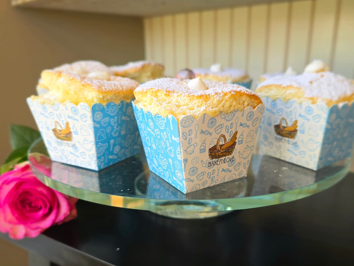 Hokkaido chiffon cupcakes with whipped cream filling, fluffy golden sponge topped with stabilized cream, on a light background