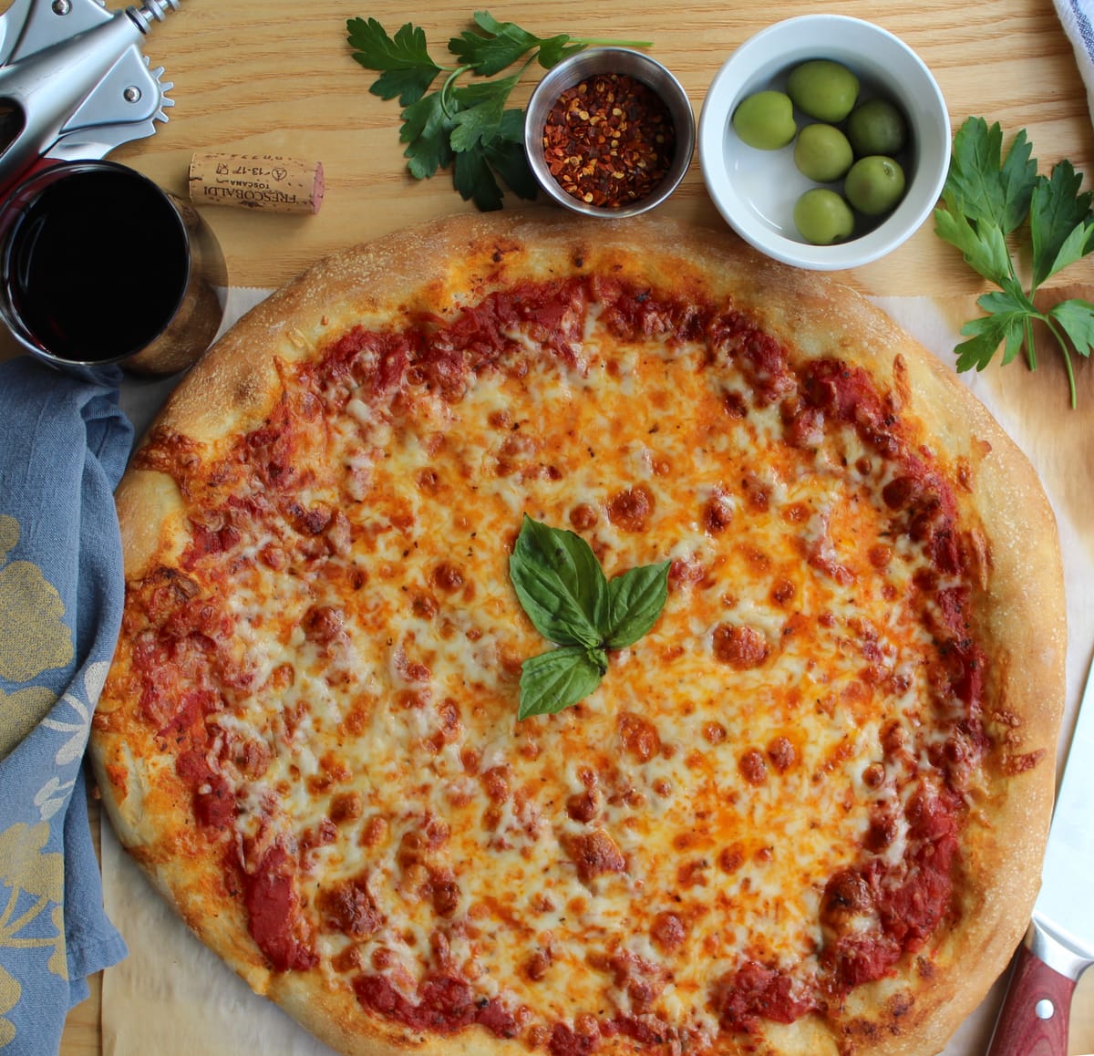 Golden crispy cheese pizza with melted mozzarella and fresh basil on a wooden surface