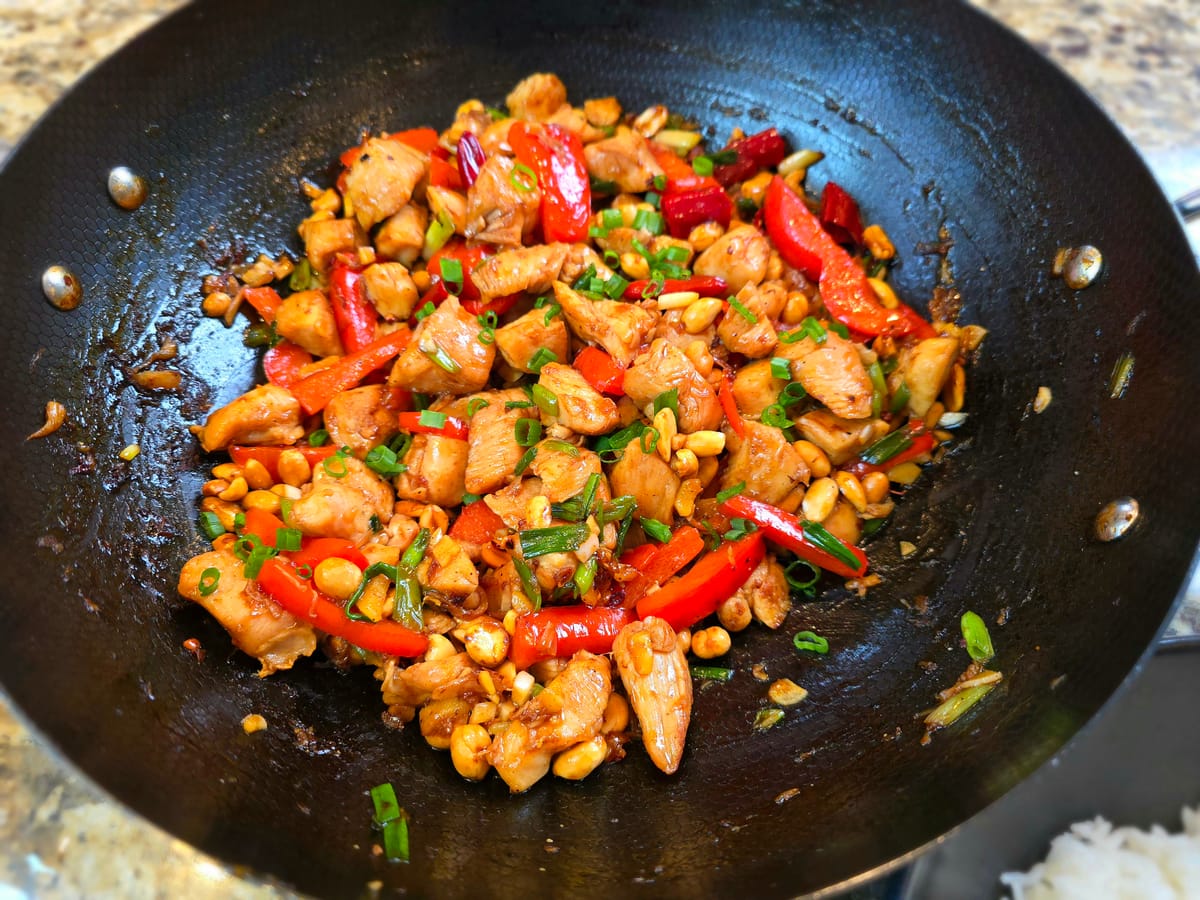 Golden Kung Pao chicken stir-fry with diced vegetables and peanuts in a wok-tossed sauce