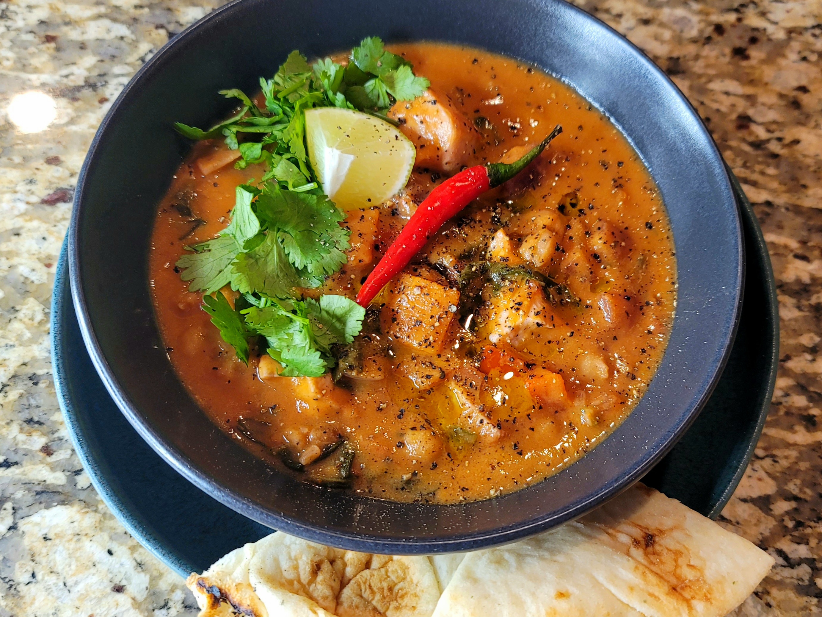 Bowl of creamy African peanut soup with diced vegetables, garnished with fresh herbs and peanuts