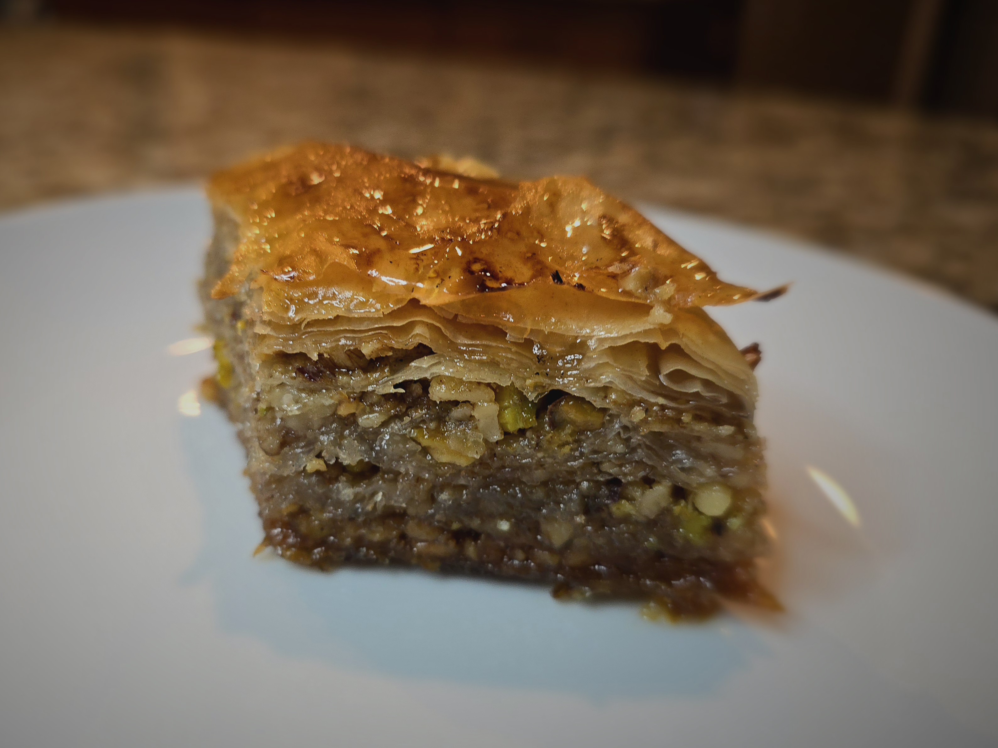 Golden crispy baklava pieces stacked together with honey dripping, showing layers of phyllo dough and chopped walnuts