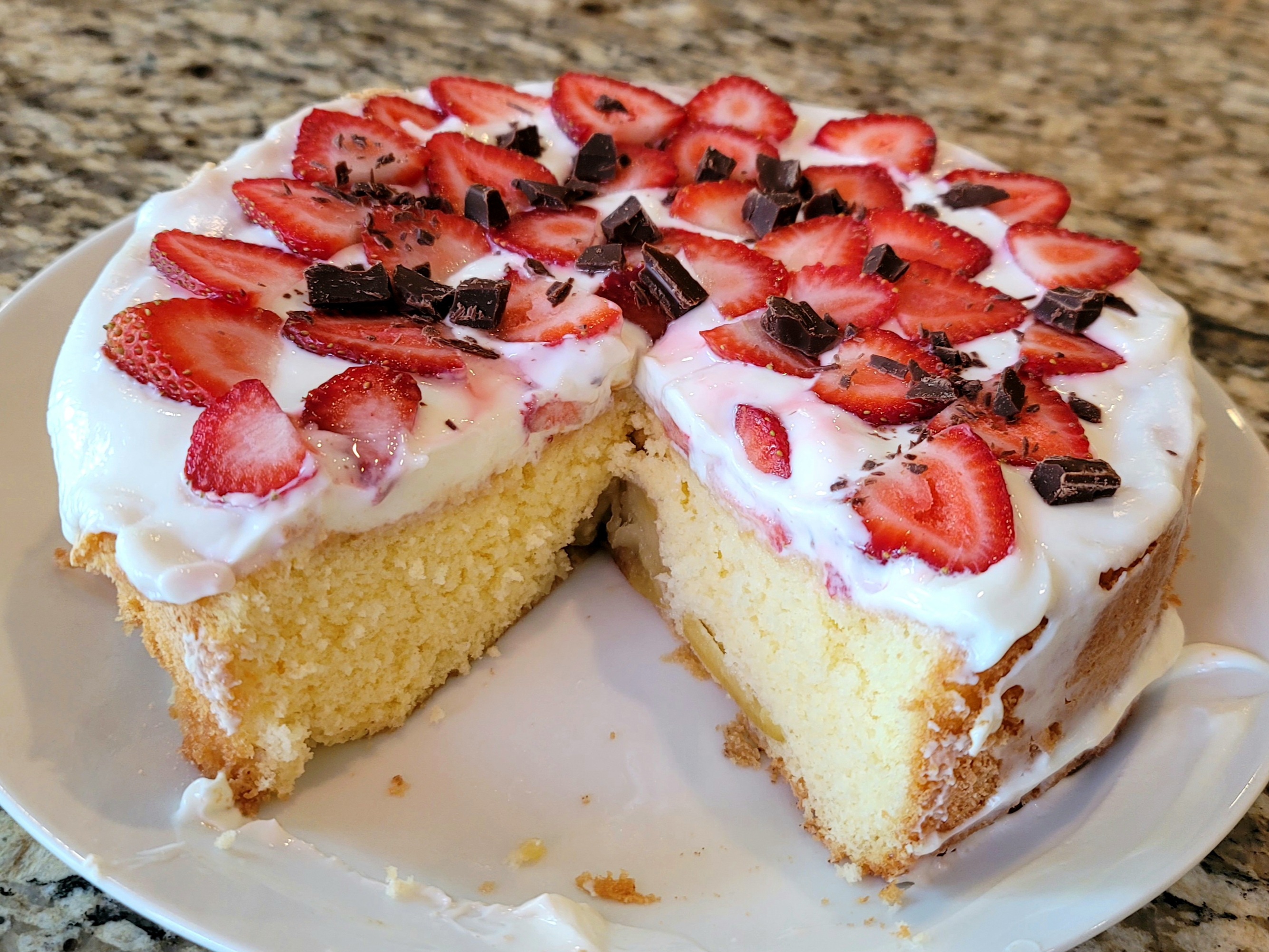 Golden Russian biskvit sponge cake layered with fresh strawberries and topped with chocolate shavings and sour cream frosting