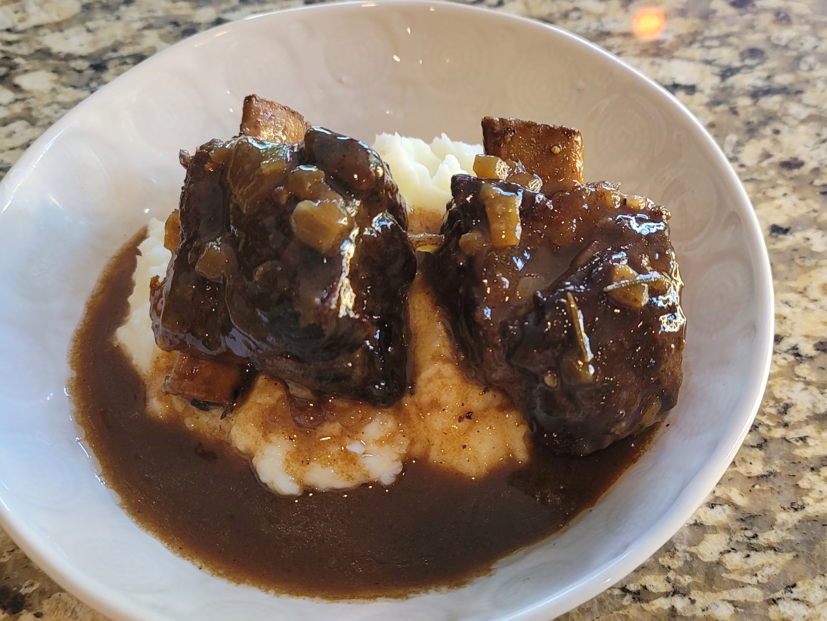 Tender braised beef short ribs with rosemary and orange in rich brown sauce