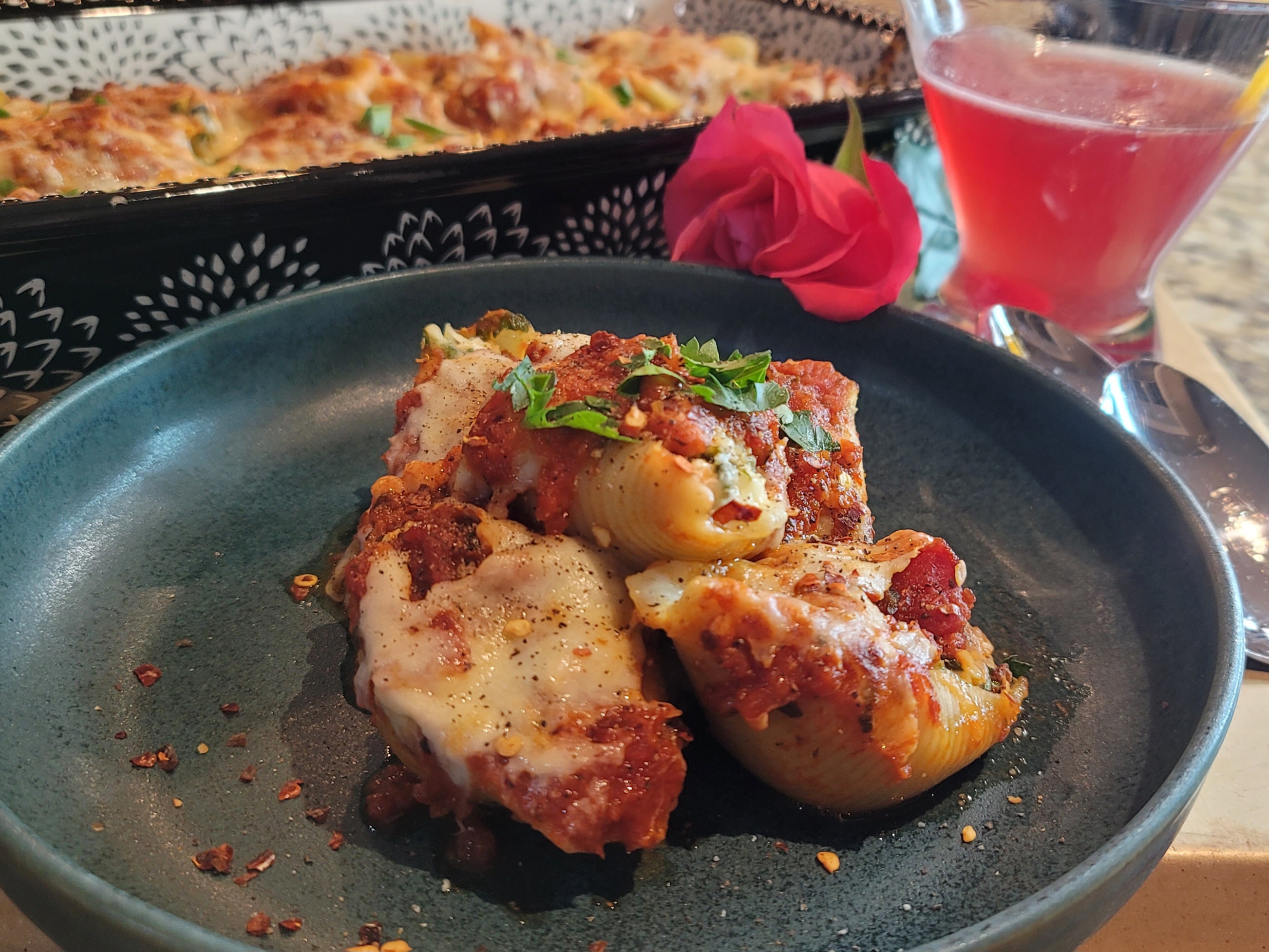 Golden-brown baked meat and cheese stuffed shells in a white dish with melted mozzarella and fresh herbs