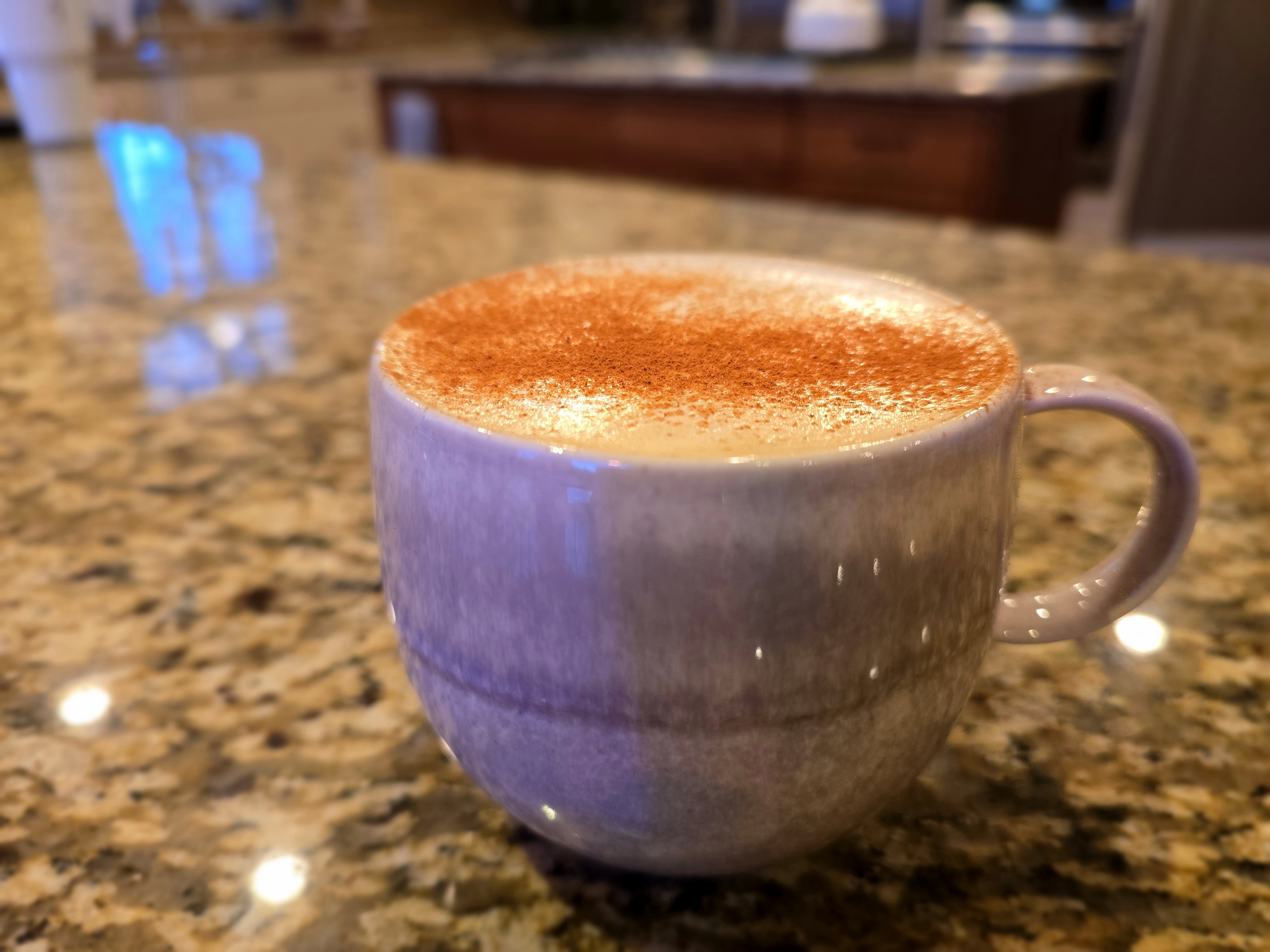 Barista-style pumpkin spice latte in a white cup with whipped cream and cinnamon on top, steaming hot