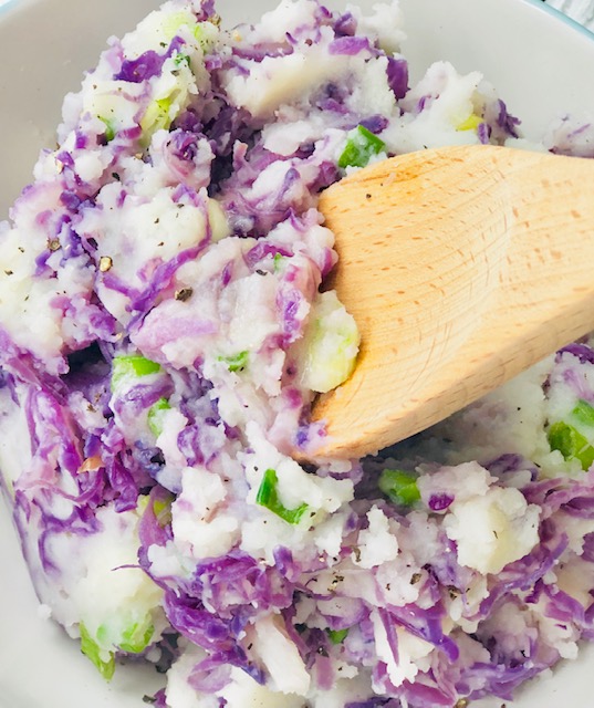Creamy red cabbage colcannon with purple and white layers of mashed potatoes and red cabbage in a white bowl