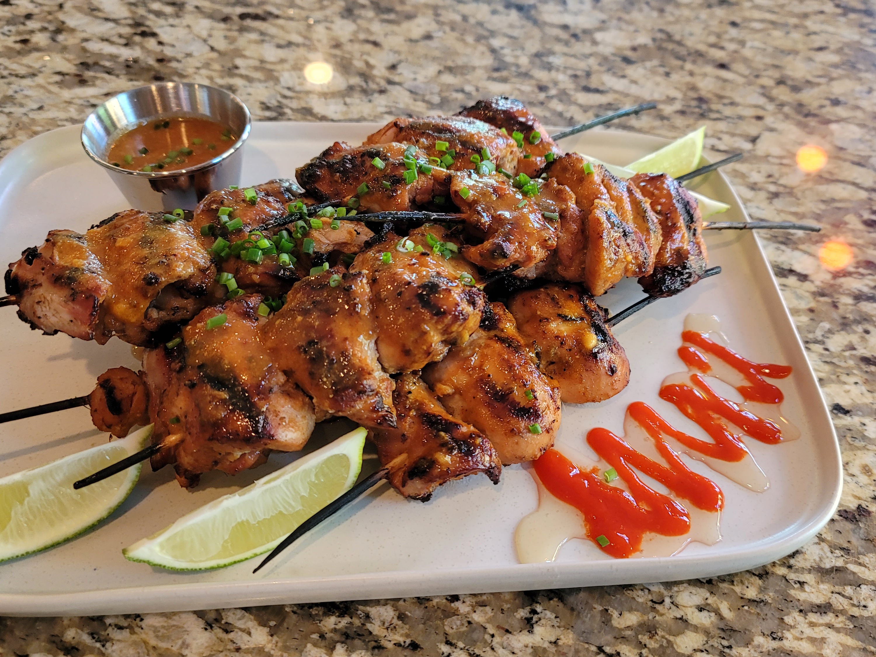 Sticky sriracha honey lime chicken thighs glazed in spicy-sweet sauce with fresh lime and garlic, plated on a white dish