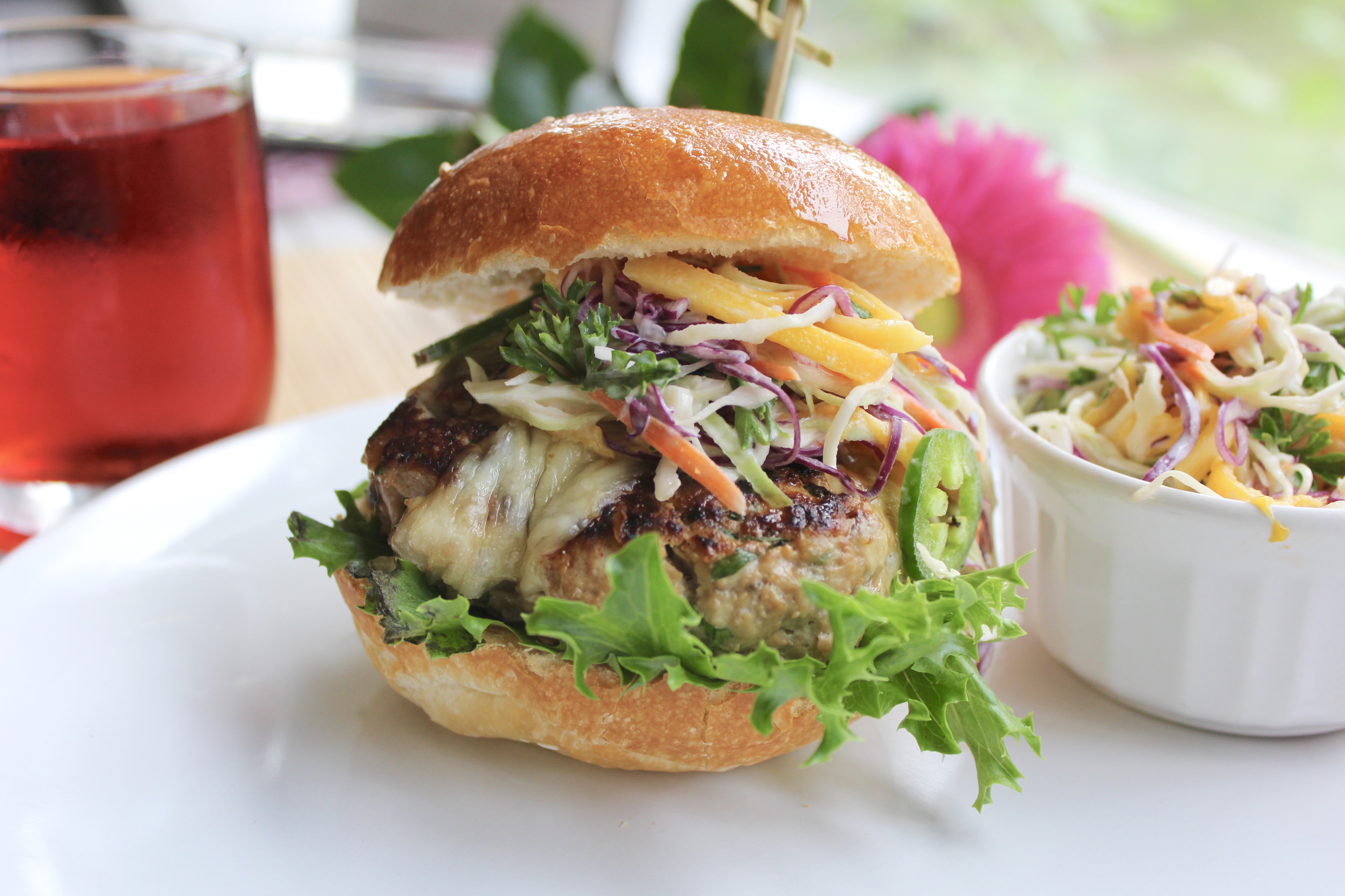 Juicy umami turkey burger on a bun with melted cheese and fresh toppings, served with fries on a white plate